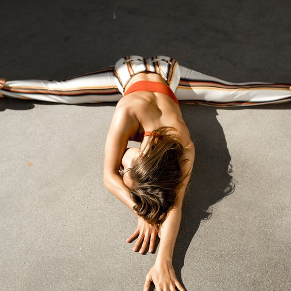 Person stretching gently outdoors with the sun shining behind them.